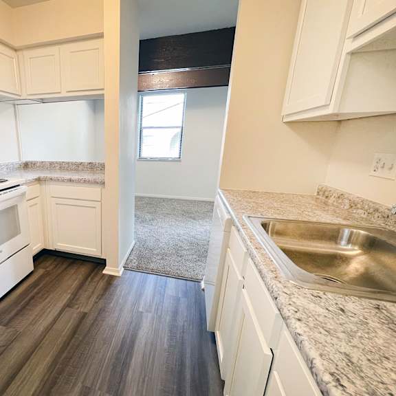 an empty kitchen with white appliances and white cabinets at four worlds apartments, ohio