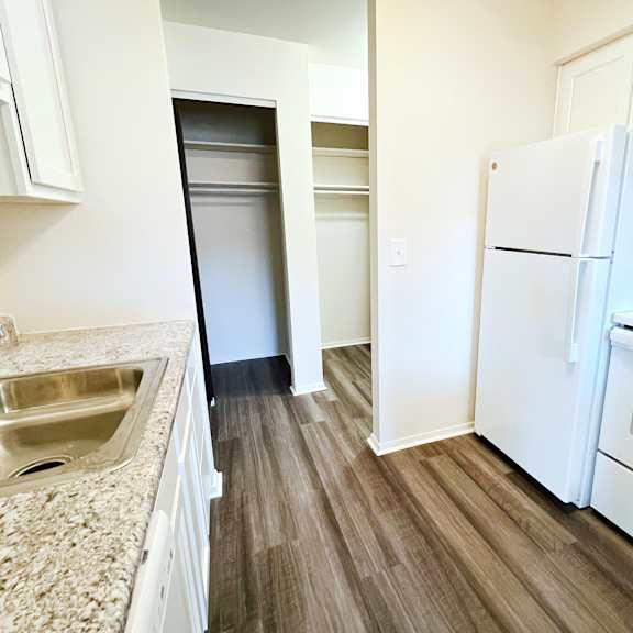 a renovated kitchen with white appliances and wood flooring at four worlds apartments, ohio