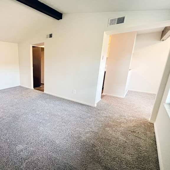 an empty living room with white walls and carpet at four worlds apartments, cincinnati, ohio