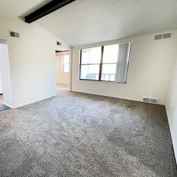 an empty living room with carpet and a window at four worlds apartments, cincinnati, 45231