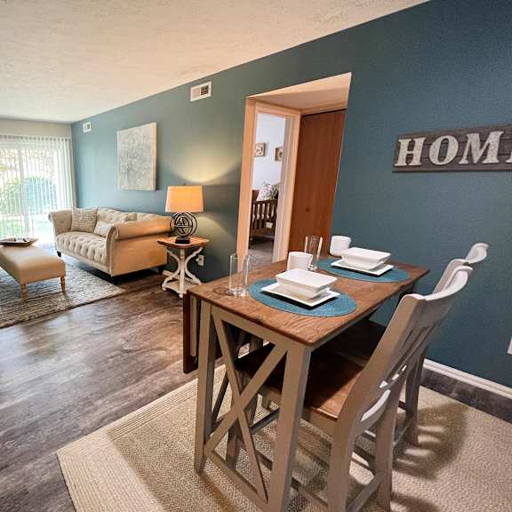 an open concept living room with a dining room table and chairs  at steeplechase apartments, loveland, ohio