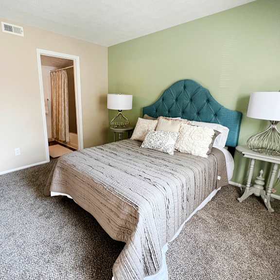 a bedroom with a bed and two lamps  at steeplechase apartments, loveland, 45140