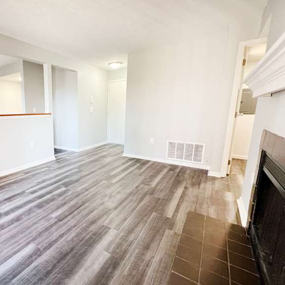 the living room and dining room of an apartment with wood flooring  at deercross apartments, ohio
