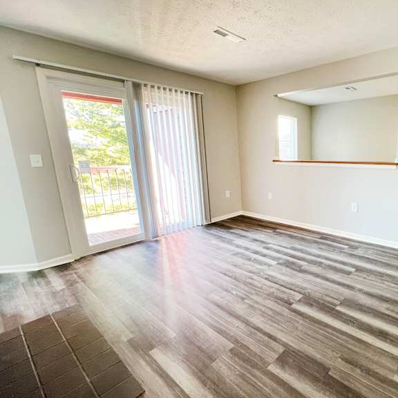 an empty living room with wood flooring and sliding glass doors  at deercross apartments, cincinnati