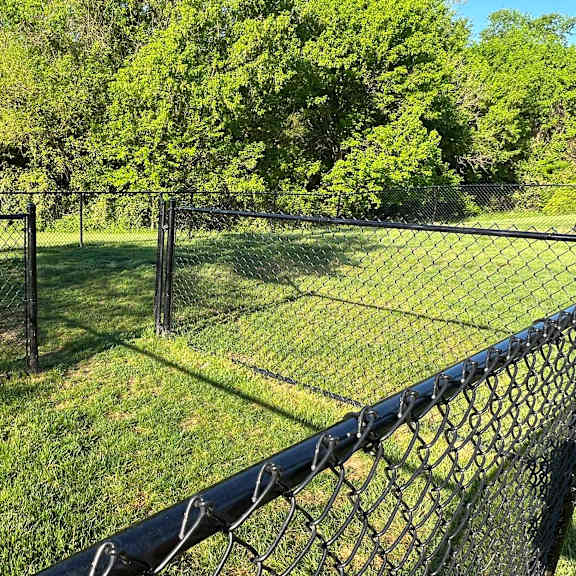 a sign is posted on a fence in a grassy area.
