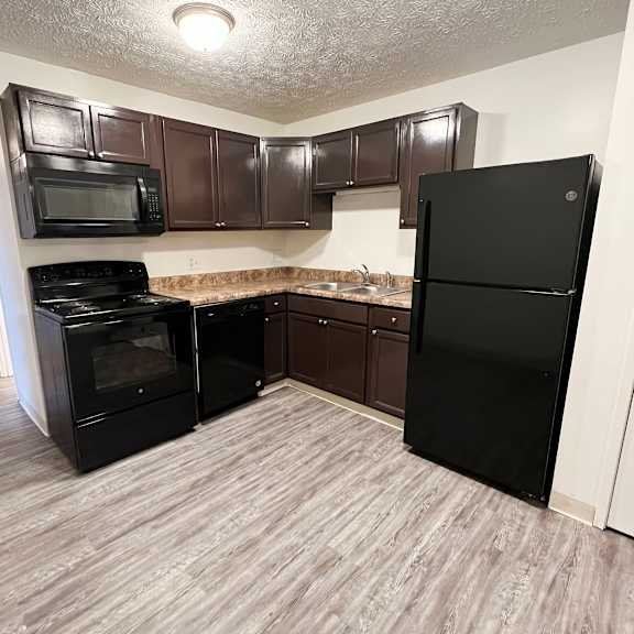 a kitchen with a black refrigerator freezer and a black stove top oven at quail meadow apartments, cincinnati, oh, 45240