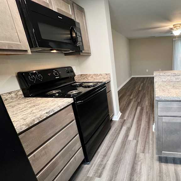 a kitchen with a black stove top oven next to a sink  at woodhills apartments, ohio, 45449
