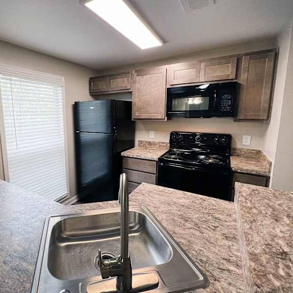 a kitchen with granite countertops and black appliances  at woodhills apartments, ohio