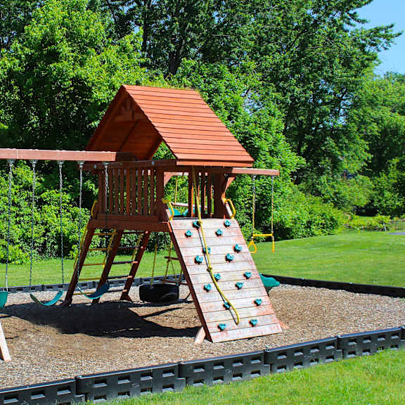 a swing set with a wooden playset in a backyard  at four worlds apartments, cincinnati, oh