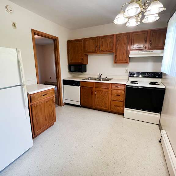 a kitchen with white appliances and wooden cabinets.