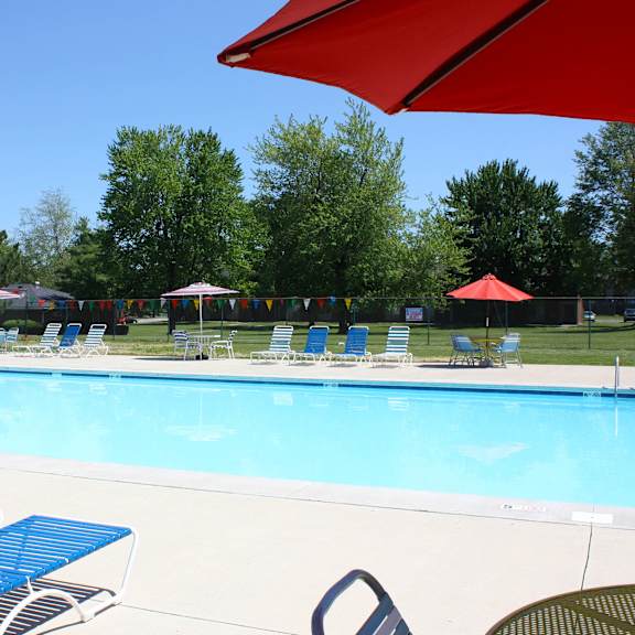 a pool with blue chairs and a red umbrella.