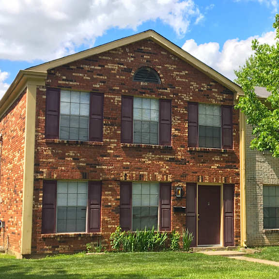 a red brick house with a tree in front.