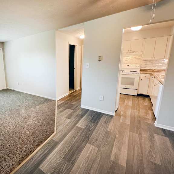 an empty living room and kitchen with wood flooring and a window at oakwood apartments, florence, ky