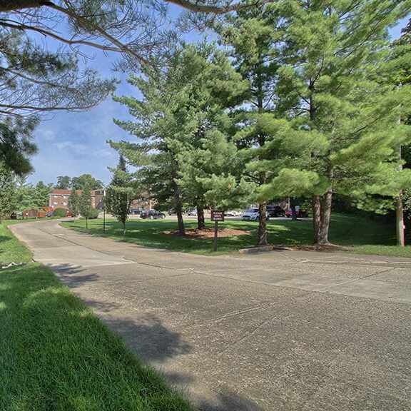 a park with trees and grass and a road with a building in the background at hunter ridge apartments, cincinnati, ohio