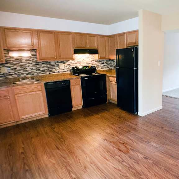 a kitchen with black appliances and wooden floors.