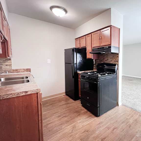 a kitchen with black appliances and wooden cabinets.