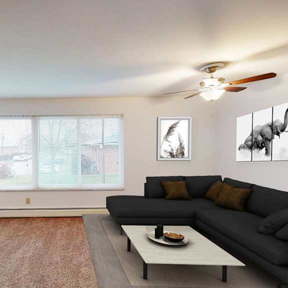 a living room with a grey couch, a black television, and a potted plant.