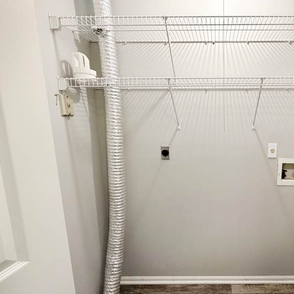 a white closet with a white pipe and a white shelf.