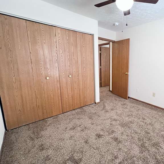 a room with a carpeted floor and a ceiling fan.