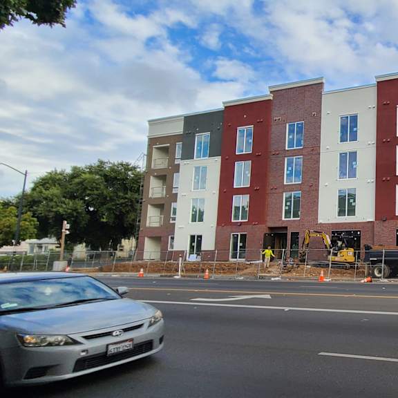 a multi-story building under construction is being built on a street corner.