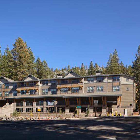 a large building with a balcony on the second floor is surrounded by trees.
