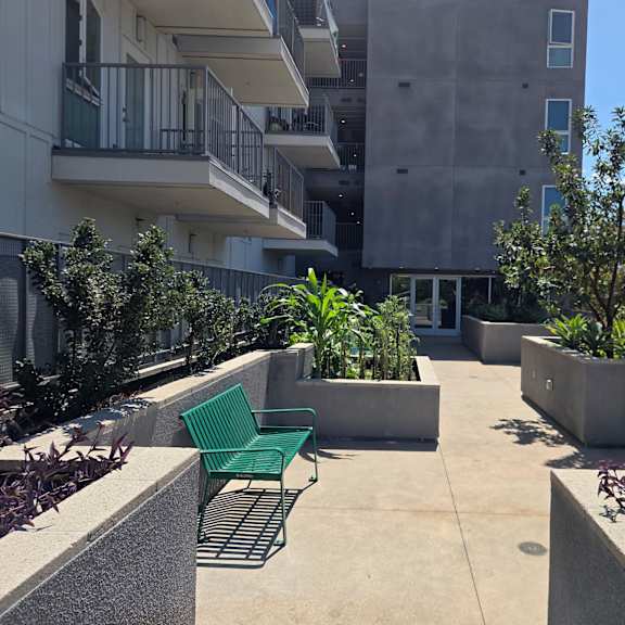 a concrete patio with green chairs and a planter box.