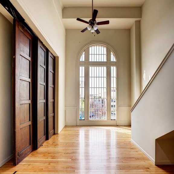a long hallway with a ceiling fan and wooden floors.