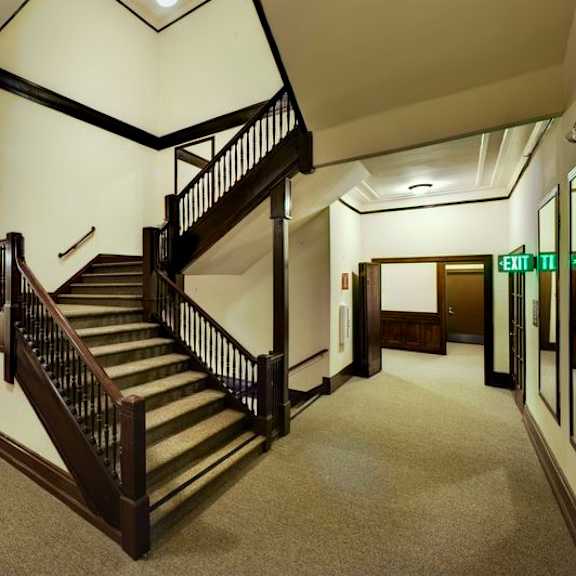 a staircase in a building with a green exit sign.