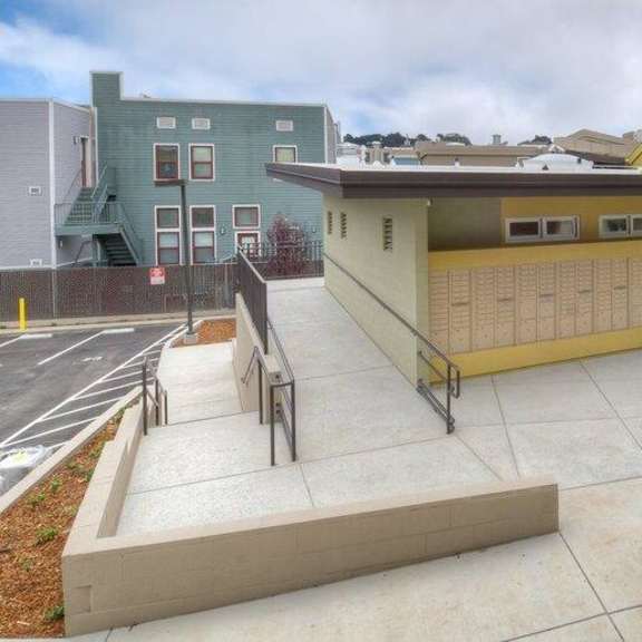 a small building with a yellow front and a grey roof.