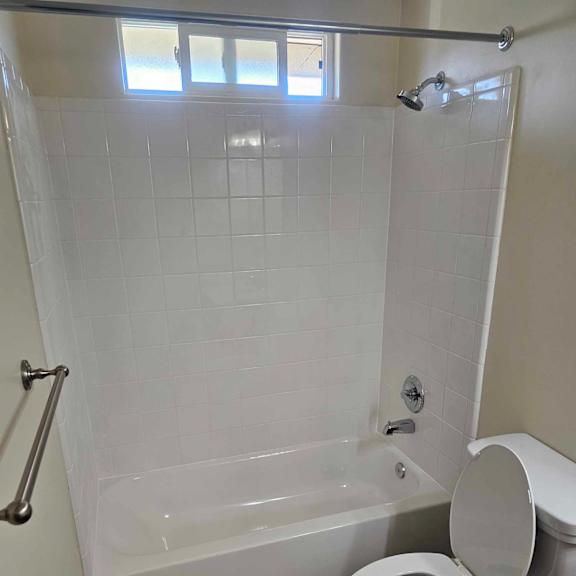 a white toilet is in a bathroom with a white tub and tiled floor.