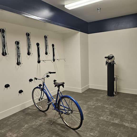 a blue bike is parked in a room with wall hooks and a bike rack.