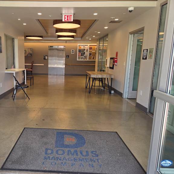 the entrance to a building with a domus management company doormat.