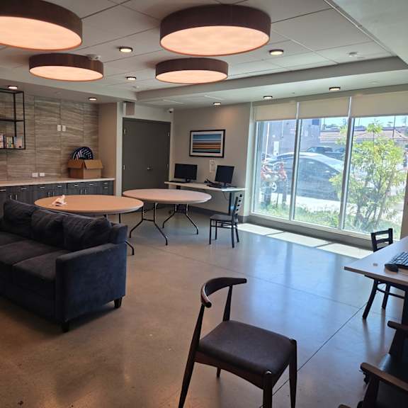 a room with a couch, chairs, and a table with a laptop on it.