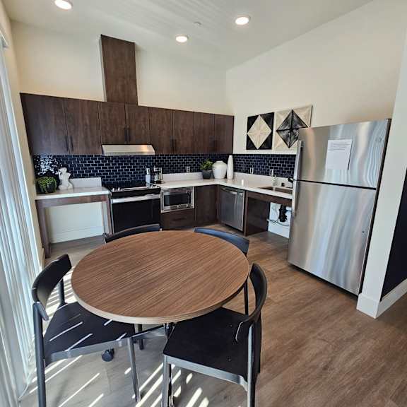 a modern kitchen with a wooden table and black chairs.