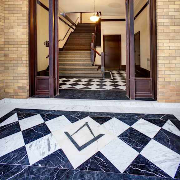 a black and white checkered floor leads up to a set of stairs.