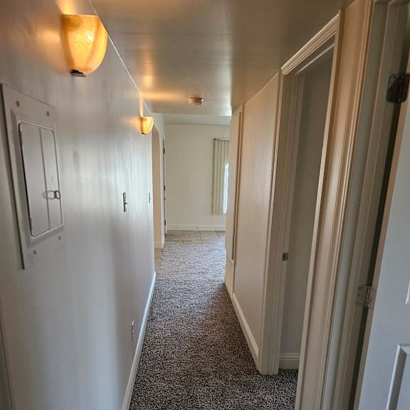 a hallway with white walls and a grey carpet.