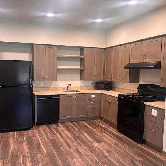 a kitchen with wood flooring and black appliances.