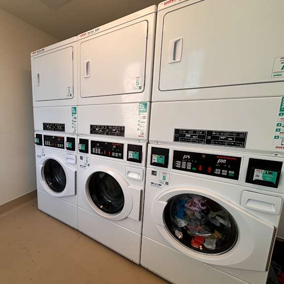 a row of white front load washing machines in a laundromat.