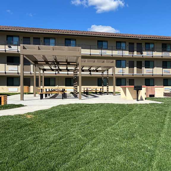 a large grassy area in front of a building with a covered walkway.