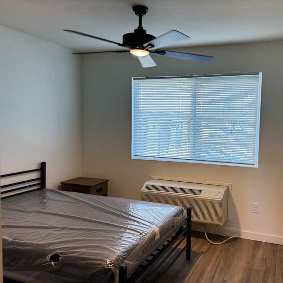 a bedroom with a bed, a ceiling fan, and a window with blinds.