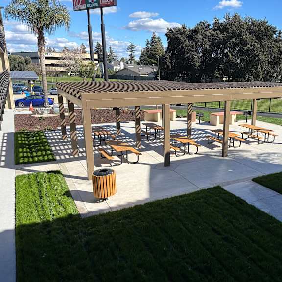 a picnic area with benches and a table is surrounded by a grassy area.