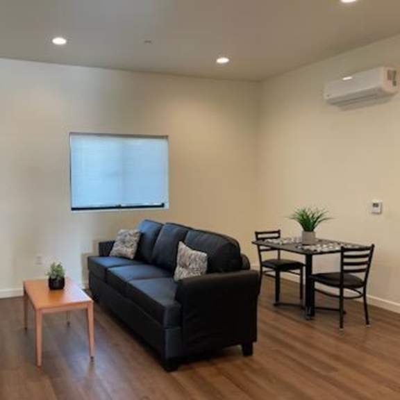 a living room with a black couch, a wooden table, and a television.