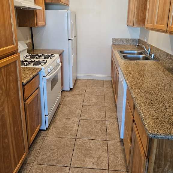a kitchen with a white refrigerator, a white dishwasher, and a white stove.