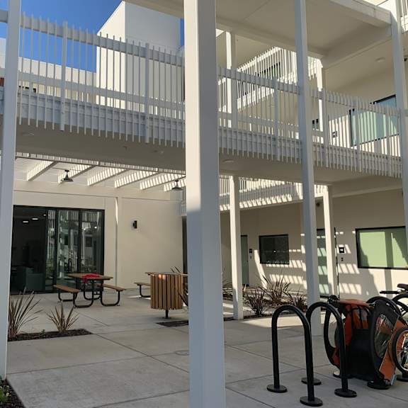 a white building with a balcony and a table and chairs outside.