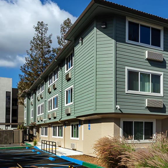 a modern apartment building with a parking lot in front.