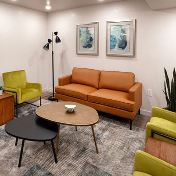 a modern living room with a grey carpet and furniture in shades of green and orange.