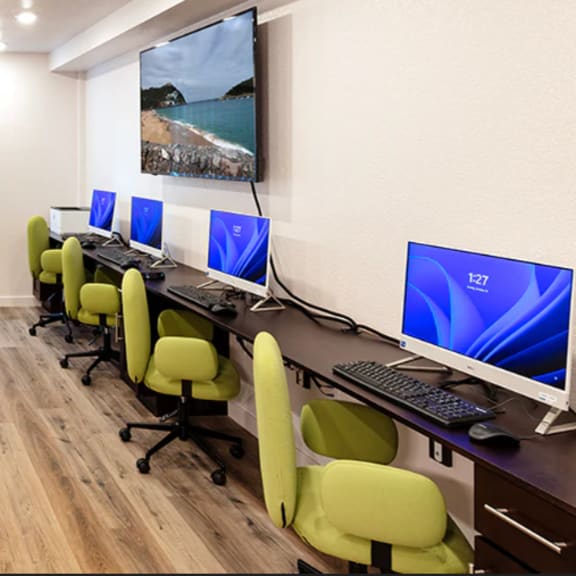 a room with a desk, chairs, and a television mounted on the wall.