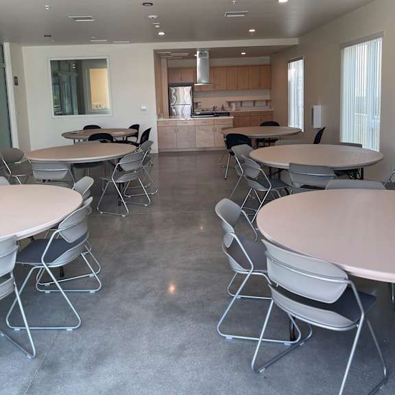 a modern kitchen with white chairs and a grey wall.