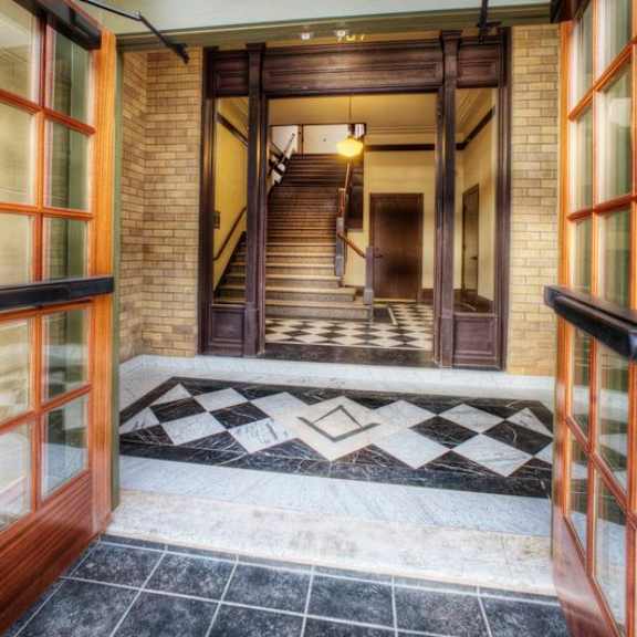a hallway with a black and white checkered floor leads to a staircase.