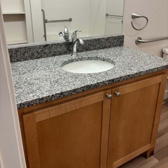 a bathroom sink with a granite countertop and wooden cabinet.